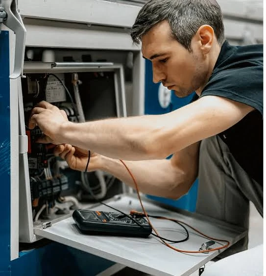 HVAC technician testing internal equipment wiring with a multimeter